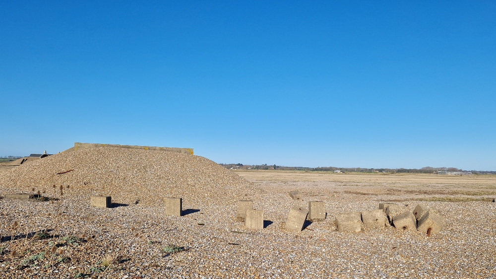 A haphazard pile of concrete blocks on the shingle at Orford Ness on a clear day